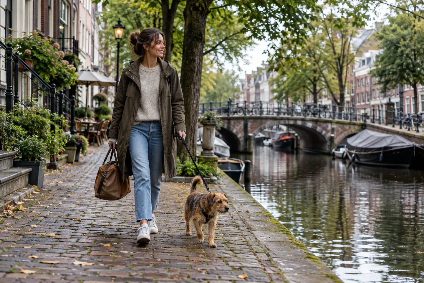 Small dog walking with owner beside a city canal